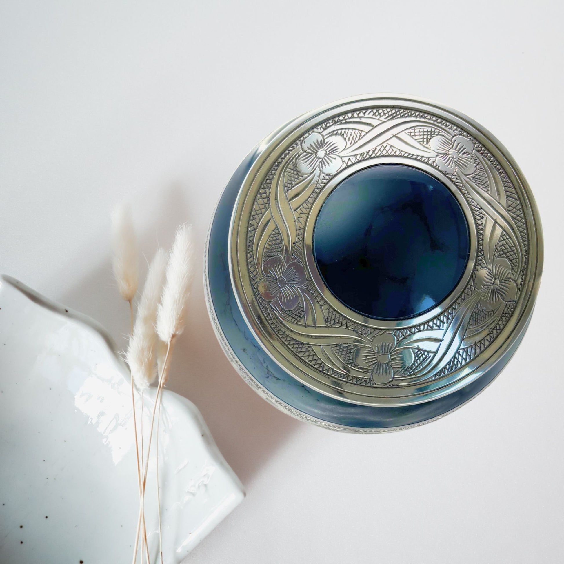 Decorative metal box with blue glass lid on a light background