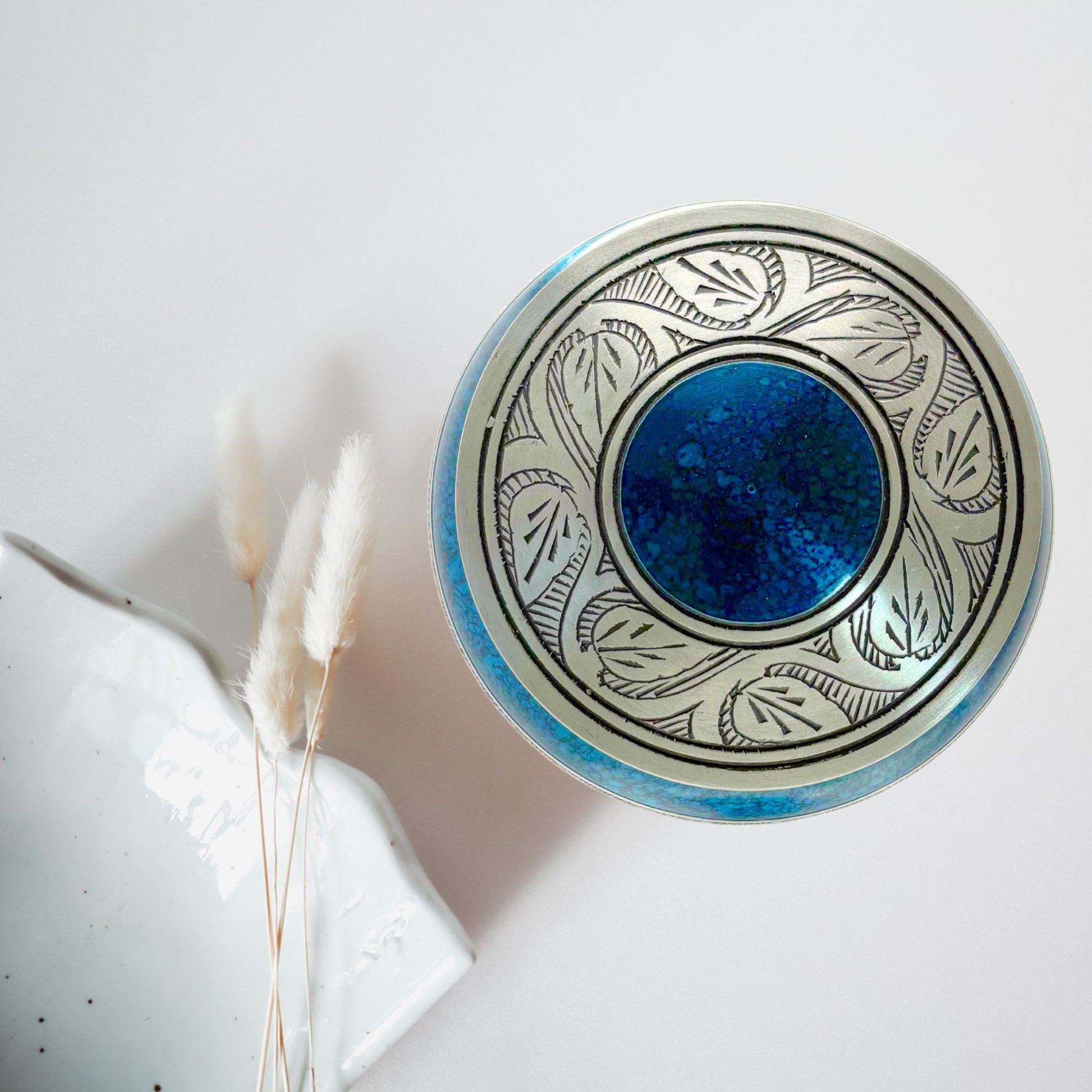 Decorative ceramic bowl with blue center and leaf patterns on a white background