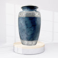 Blue marble-patterned urn with silver decorative band on a white background