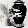 Black urn with silver fish designs on a white background