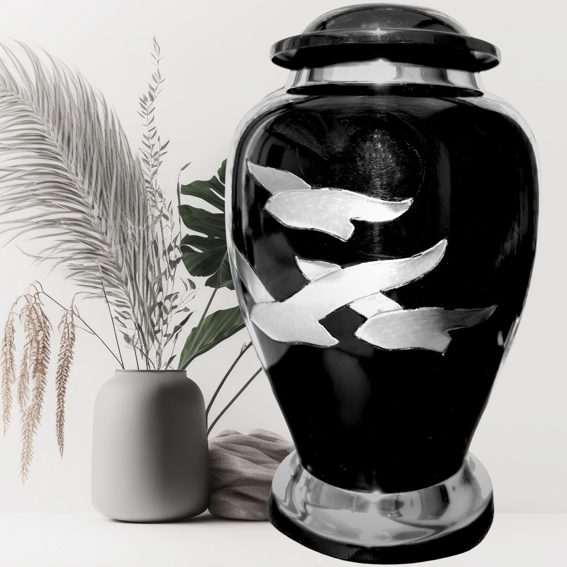 Black urn with silver fish designs on a white background