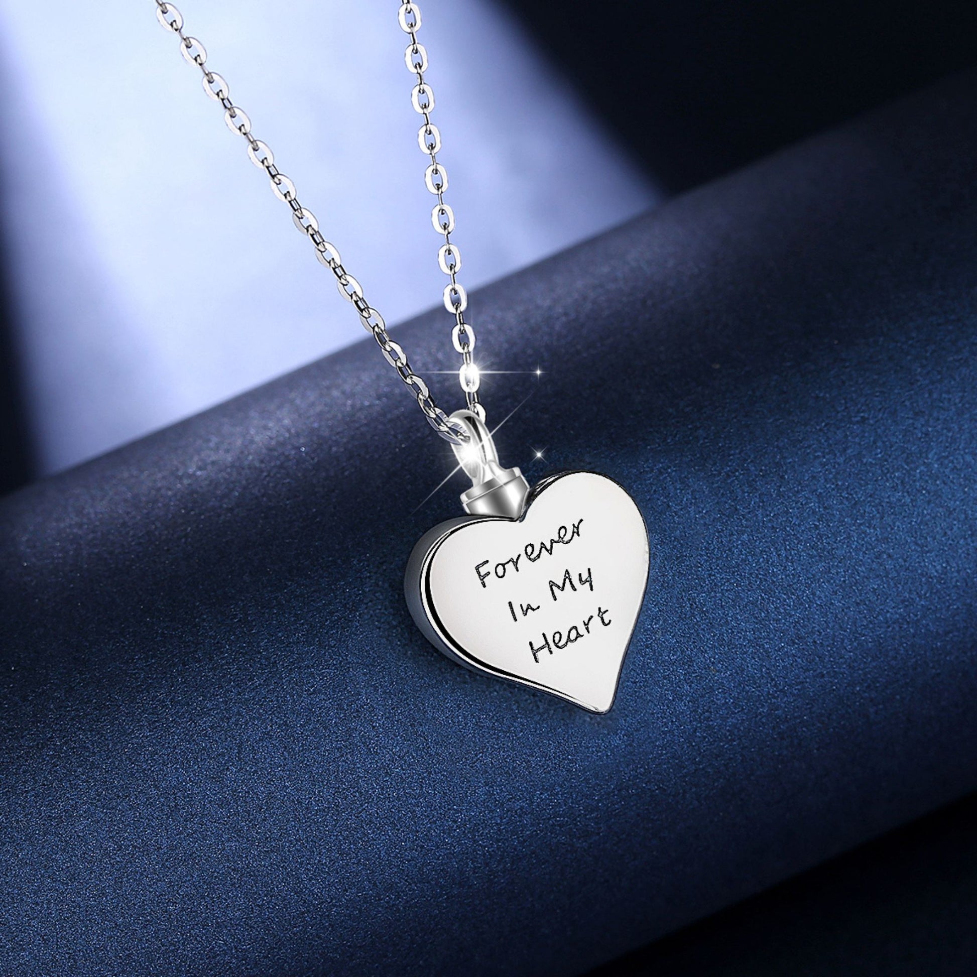 Heart-shaped silver pendant with 'Forever In My Heart' engraving on a dark blue background