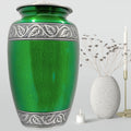 Green urn with silver leaf patterns on a gray background