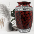 Red and black patterned urn with decorative elements on a white background