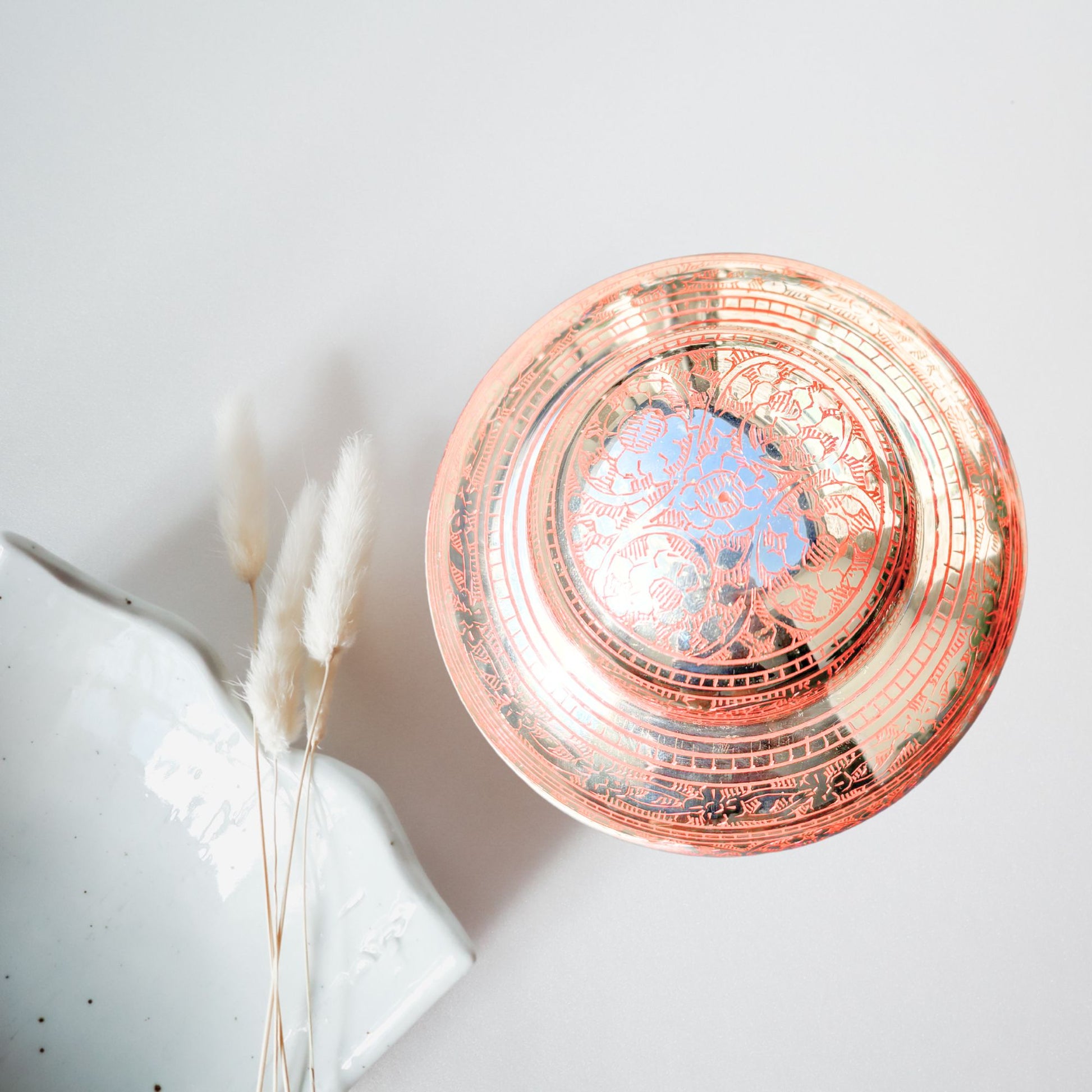 Decorative rose gold bowl with intricate patterns on a light gray background
