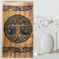 Wooden panel with tree of life design next to a vase and candle on a light gray background