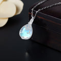 Silver necklace with a blue teardrop pendant on a dark surface
