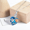 Necklace with a blue heart-shaped pendant featuring a bird design on a wooden block.