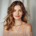 Woman wearing a necklace with a clear pendant against a neutral background