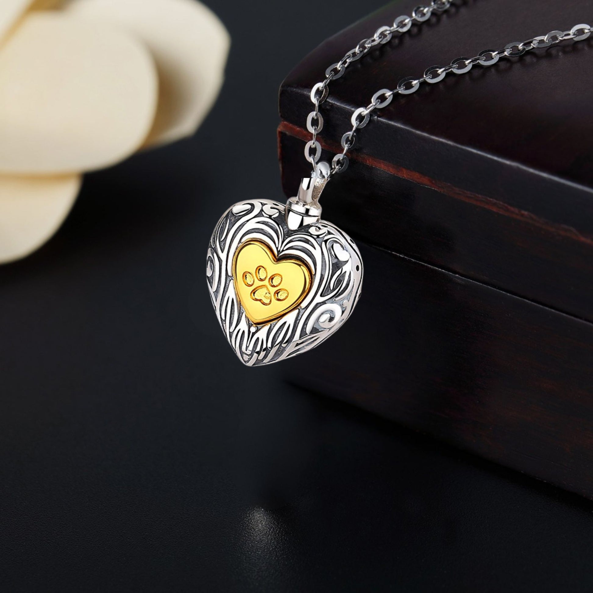 Heart-shaped silver pendant with a gold center on a dark surface
