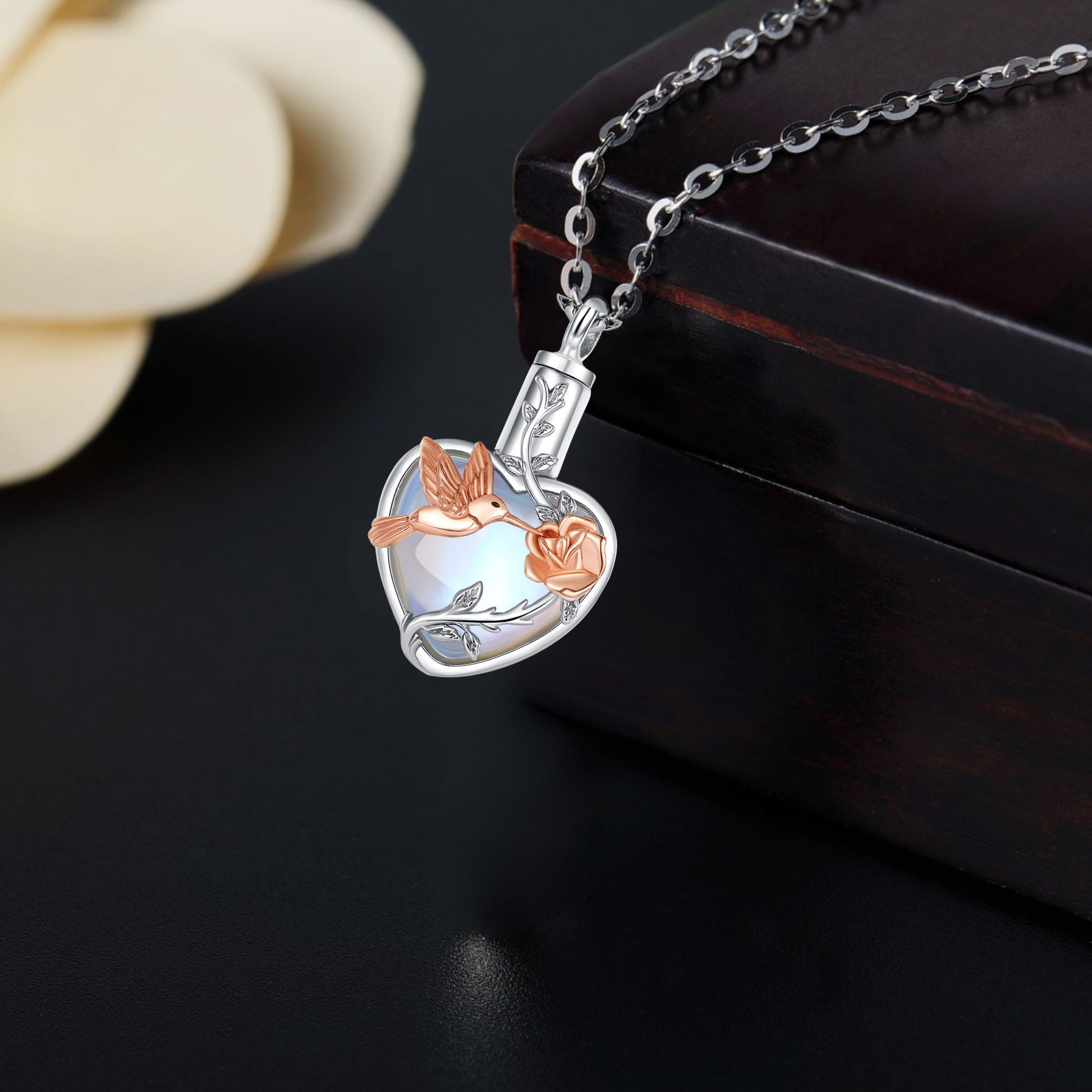 Silver and rose gold pendant on a chain against a dark background