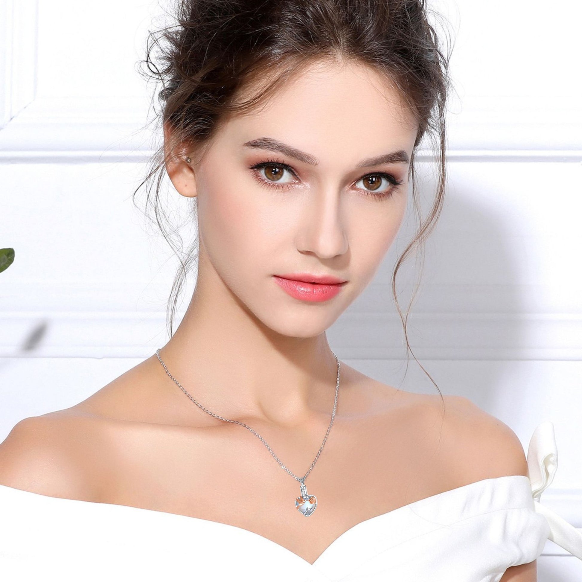 Woman wearing a silver necklace with a clear pendant against a white background