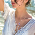 Woman wearing a necklace with a pendant by the water